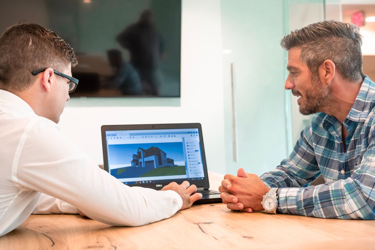 Two colleagues reviewing work on a laptop